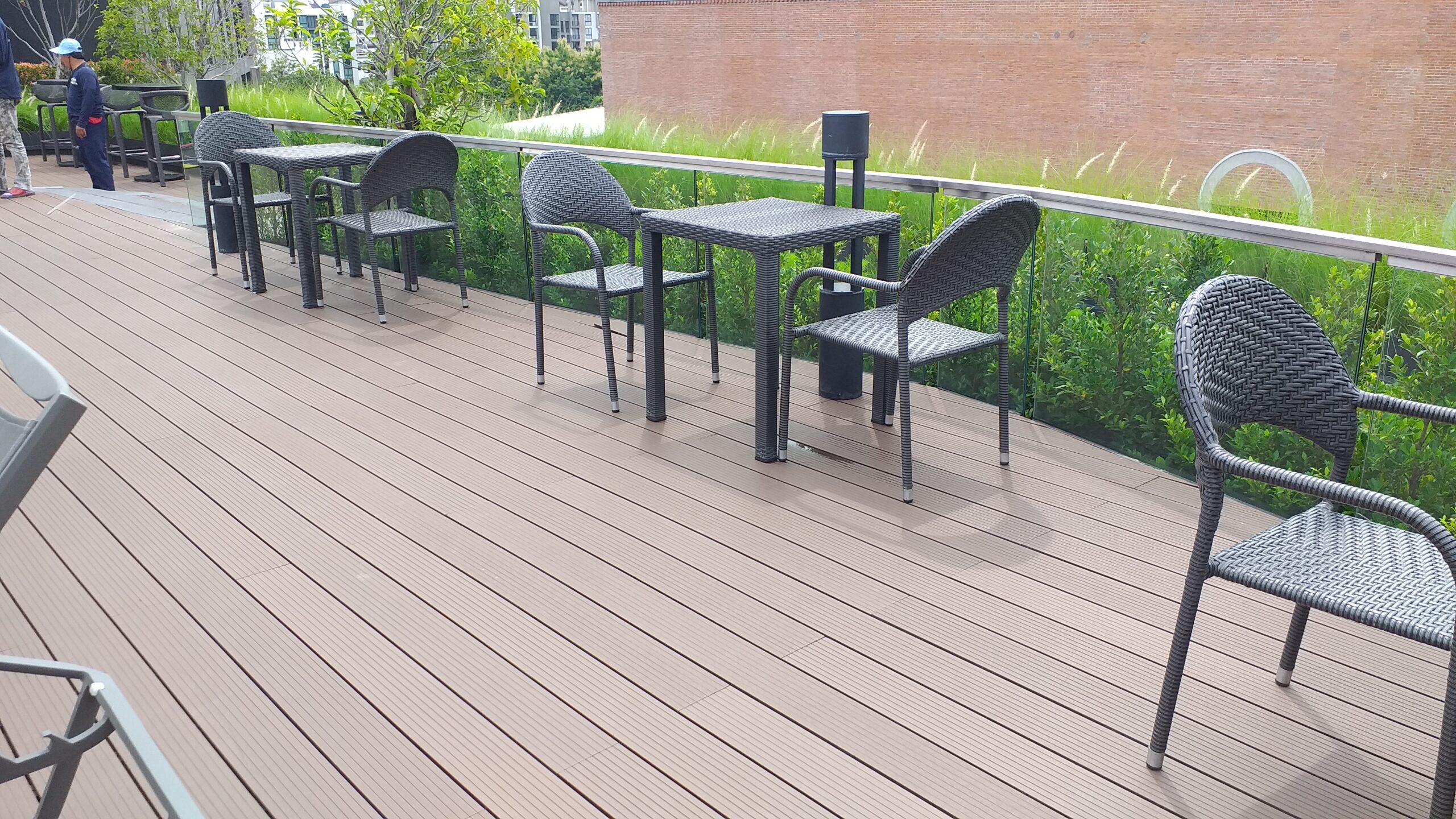 พื้นที่พักผ่อนบนดาดฟ้า ปูด้วยพื้นไม้ WPC สีน้ำตาล พร้อมชุดโต๊ะเก้าอี้หวาย ให้ความรู้สึกผ่อนคลาย